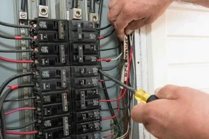 Electrician repairing a circuit breaker panel and inspecting electrical wiring.