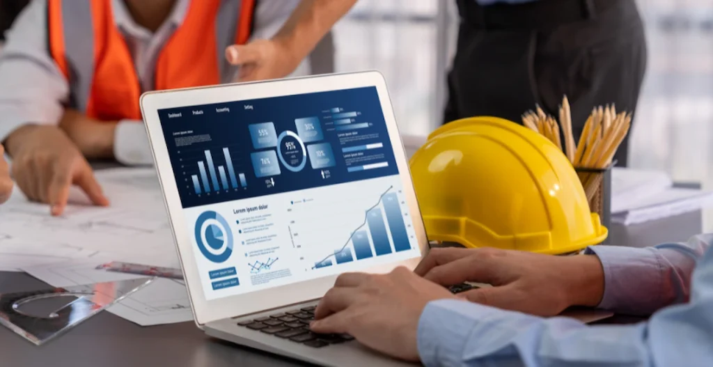 Construction team reviewing project analytics and planning data on a laptop at a job site.