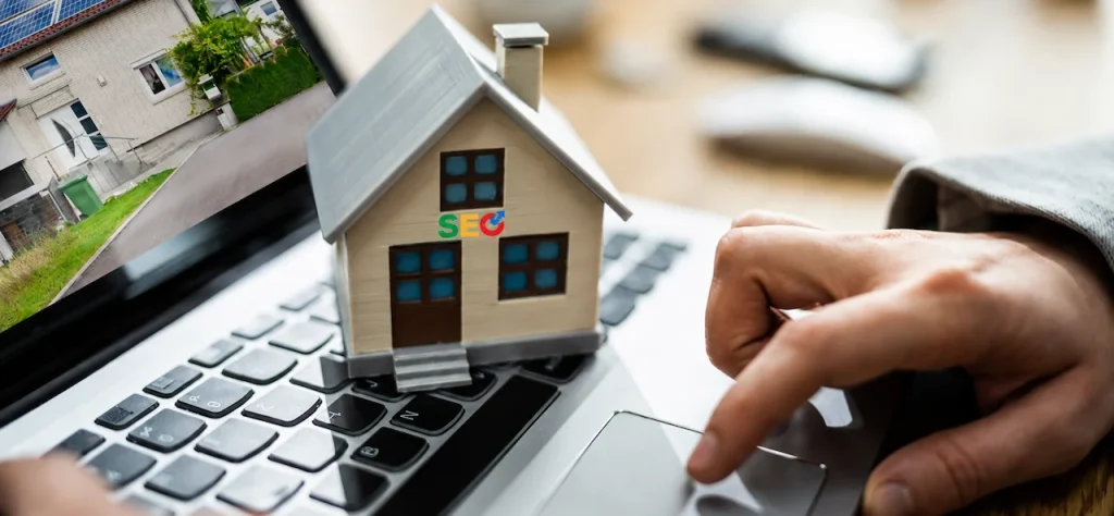 Real estate SEO concept showing a house model on a laptop keyboard with property search and marketing tools.