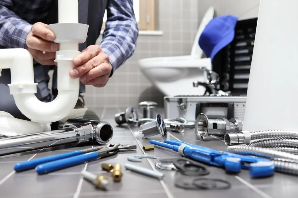 Professional plumber repairing bathroom pipes with plumbing tools and fixtures in a California home.