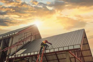 Professional roofing contractor installing a metal roof on a commercial building during a sunset construction project.