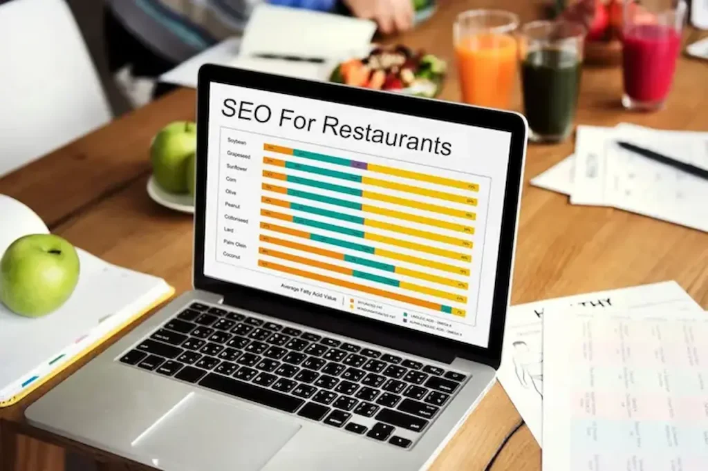 Laptop displaying restaurant SEO performance dashboard with keyword rankings and analytics report on a restaurant table.