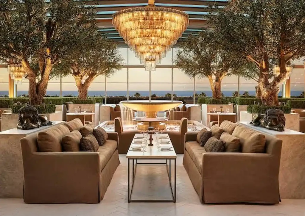 Luxury restaurant interior in California featuring elegant dining areas, chandeliers, indoor trees, and upscale seating for a premium dining experience.