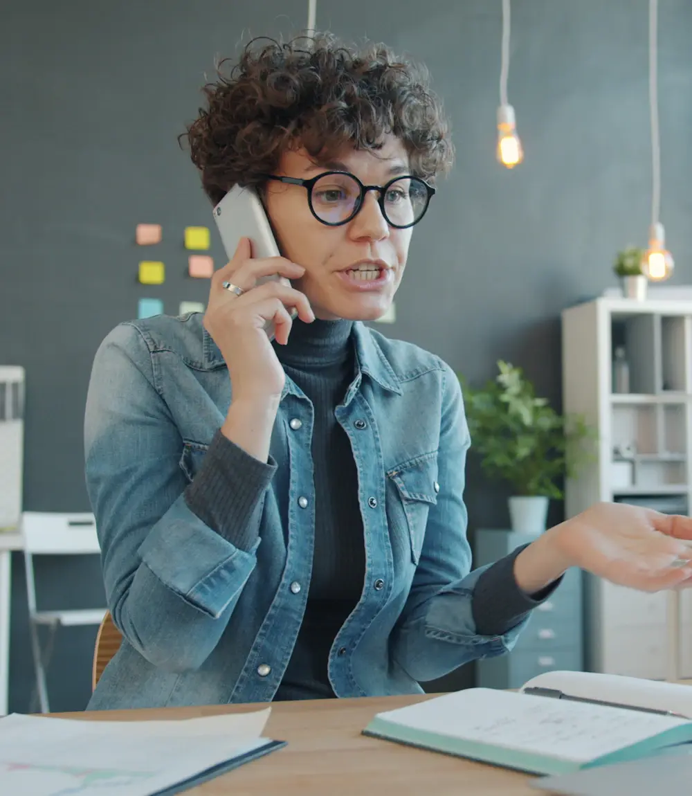 Sales rep following up with a new lead by phone at her desk