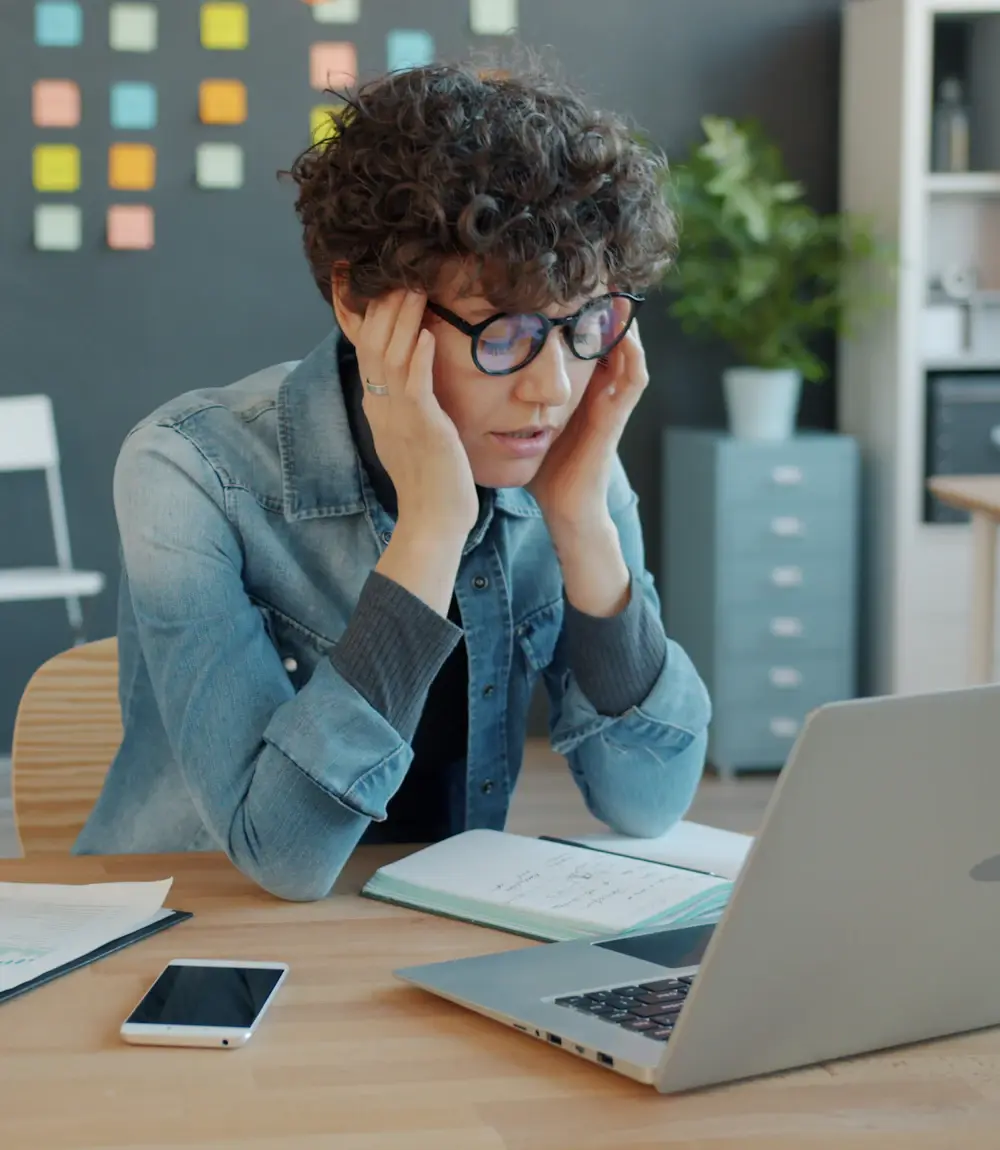 Office worker stressed by repetitive manual admin work at a laptop